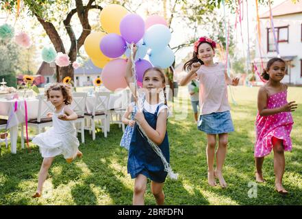 Niños pequeños al aire libre en el jardín en verano, jugando con globos.