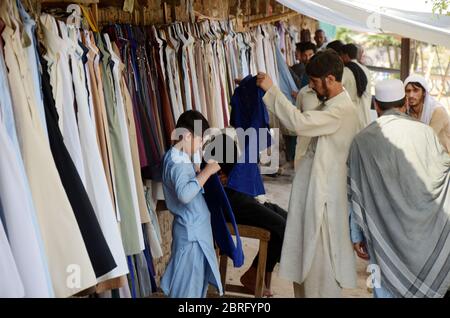 Peshawar, Pakistán. 21 de mayo de 2020. Un hombre vende ropa usada antes  que Eid al-Fitr en Peshawar. Eid al-Fitr es una fiesta islámica que Marca  el final del Ramadán, y se celebra durante los primeros tres días de  Shawwal, el décimo mes del 