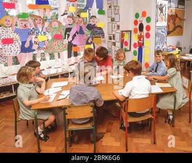 Profesor ayudando a los niños de la escuela primaria en clase de arte, Surrey, Inglaterra, Reino Unido
