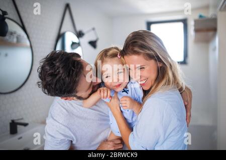 Familia joven con una hija pequeña en el baño, abrazando.