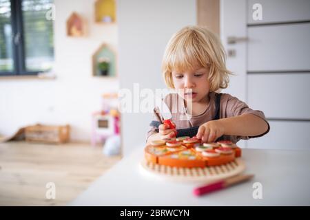 Un pequeño niño pequeño y lindo dentro del dormitorio jugando.