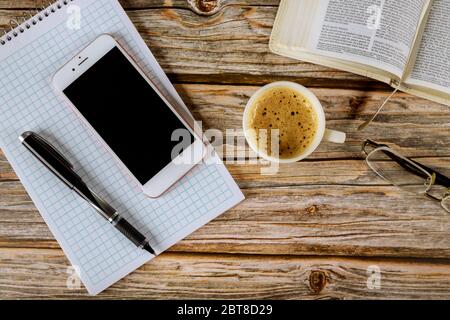 Foto Bíblia aberta ao lado de xícara de café e smartphone na mesa