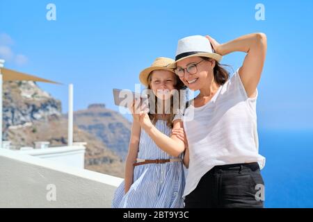 Felices turistas madre e hija tomando foto selfie, isla de Santorini