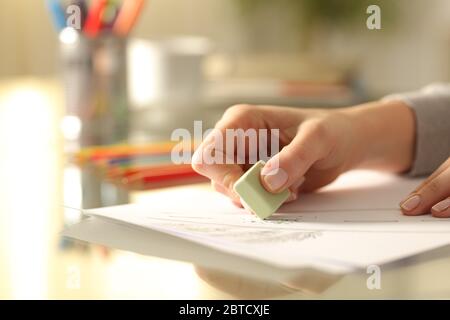 Primer plano de manos de la mujer borrando dibujo con goma en el escritorio en casa