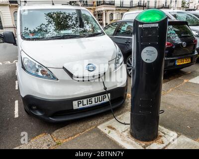 Un coche eléctrico Nissan Leaf estacionado y conectado a una estación de carga eléctrica en el centro de Londres. Foto de stock