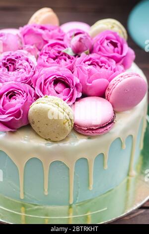 Pastel de color turquesa con chocolate blanco derretido, rosas frescas y  decoración de macarrones franceses. Fondo de madera rústica Fotografía de  stock - Alamy