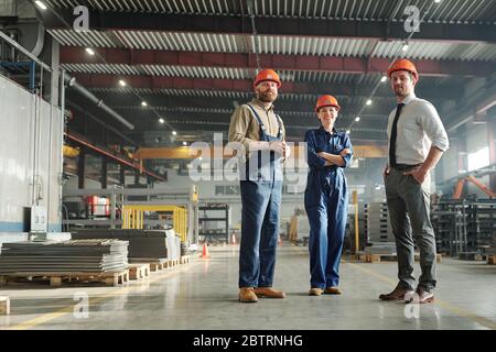 Ambiciosos profesionales de fábrica contemporánea en la tienda industrial y trabajando en equipo