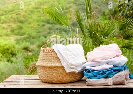 Cesta con ropa limpia y seca sobre mesa de madera sobre fondo natural en el  día soleado Fotografía de stock - Alamy