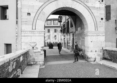 VERONA, ITALIA - 14, MARZO de 2018: Imagen en blanco y negro de la gente en Ponte Pietra, un famoso puente de Verona, Italia Foto de stock