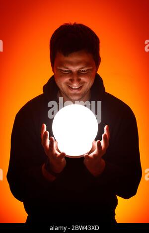 Hombre con una bola luminosa en sus manos.
