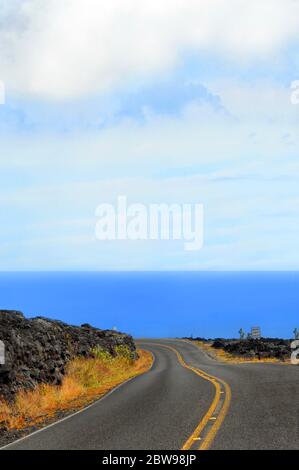 Gran extensión de azul espera al final de esta sinuosa carretera en el Parque Nacional de los Volcanes de Hawai en la Gran Isla de Hawai. Foto de stock