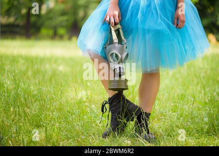 Mujer en falda azul con máscara de gas de pie sobre hierba verde en un parque. Protección ambiental, riesgo biológico y concepto ecológico