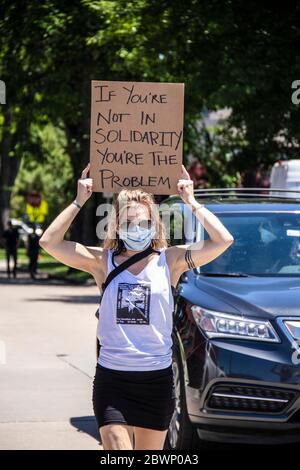 05-30-2020 Tulsa USA - Mujer con mini-falda y F hombres camiseta camina con el signo sostenido sobre su cabeza leyendo Si no estás en solidaridad eres el proble