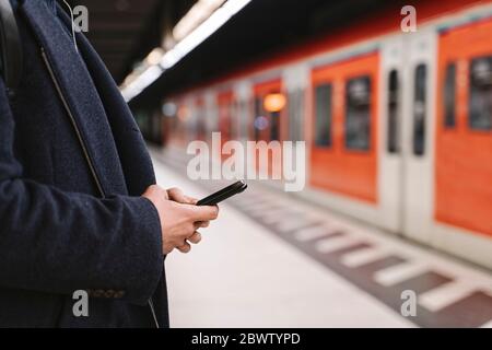 Primer plano de hombre utilizando el smartphone en la estación de metro Foto de stock