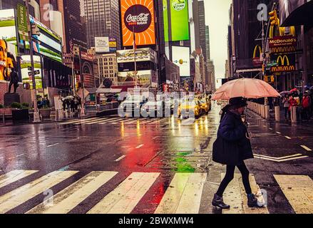 Ciudad de Nueva York, EE.UU., 2019 de mayo, mujer cruzando la carretera en un día de lluvia en W46th St & 7th Ave, Manhattan