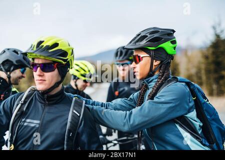 Grupo de ciclistas de montaña de pie en la carretera al aire libre en invierno, hablando. Foto de stock