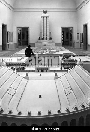 Un hombre analiza el diseño general del recinto del Partido Nazi en Nuremberg, creado por Albert Speer y Walter Brugmann, en el Haus der Deutschen Kunst de Munich. En primer plano el Deutsches Stadion. Detrás de ella el campo de Maerzfeld y Zeppelin. En el fondo, el Pabellón Alemán de la exposición Mundial en París 1937, también diseñado por Albert Speer.