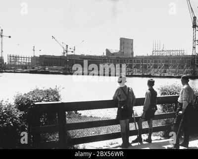 Un hombre (con muleta) y dos chicos miran al Grosse Dutzendteich en el lugar de construcción del Palacio de Congresos, planeado por los arquitectos Ludwig Ruff y Franz Ruff en el campo de concentración del Partido Nazi en Nuremberg. Foto de stock