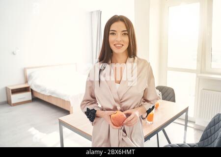 Mujer joven bastante posando en casa con una manzana en las manos Mujer joven bastante posando en casa con una manzana en las manos