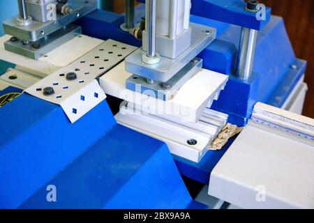 Máquina industrial para cortar perfiles plásticos en color blanco y azul Foto de stock