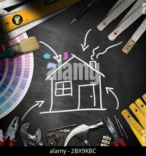 Concepto de mejora del hogar - Pizarra negra con herramientas de trabajo y un dibujo tiza de una casa