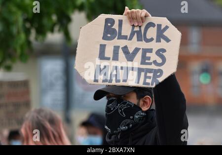 Un manifestante masculino en un mitin contra el racismo en el Reino Unido sosteniendo un cartel que dice "Black Lives Matter"