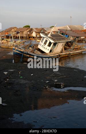 Un barco pesquero varado en la zona intermareal cerca de la aldea de pescadores de Marunda en el norte de Yakarta, Región de la Capital Especial de Yakarta, Indonesia. Foto de stock
