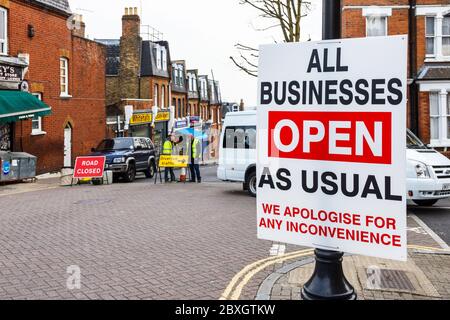 Un cartel que dice "Empresas abiertas como de costumbre" al lado de una carretera cerrada para filmar en el norte de Londres, Reino Unido