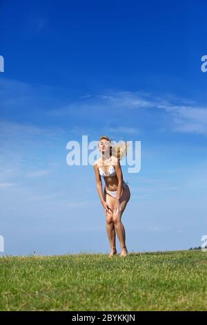 mujer en un campo verde de verano contra el cielo azul Foto de stock