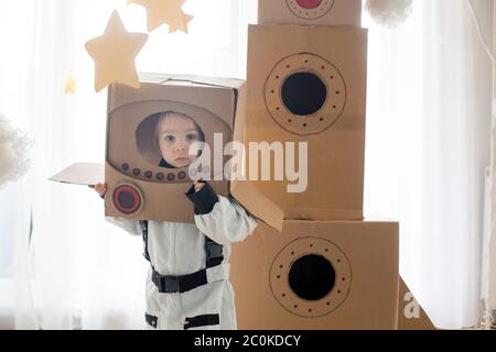 Dulce niño pequeño, vestido como astronauta, jugando en casa con cohete de  cartón y casco hecho a mano de la caja Fotografía de stock - Alamy