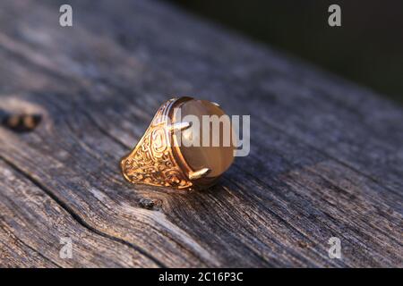 Hombres musulmanes aqeeq anillo de humor con calcedonia amarilla agate piedra preciosa sobre madera. Los machos islámicos de las culturas árabes usan anillos akik o aqiq en sus manos