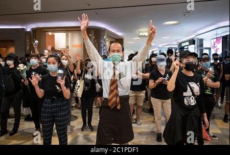 HONG KONG,HONG KONG RAE,CHINA: 15 DE JUNIO DE 2020. Los manifestantes sostienen el cartel de mano "5 exige no menos" en Pacific Place Mall en Admiralty Hong Kong. Están allí para conmemorar la muerte de los primeros manifestantes democráticos hace un año. Marco Leung cayó a su muerte por andamios fuera del edificio el 15 de junio de 2019. Se le conoció como el hombre impermeable. Imagen de stock de Alamy/Jayne Russell