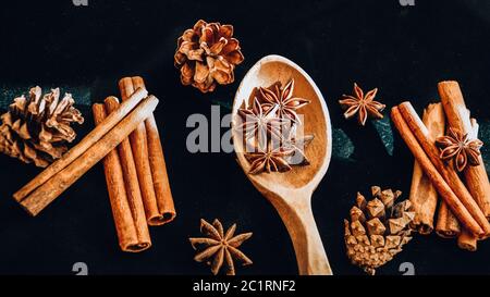 cuchara de madera con anís estrellado, bastones de canela, conos, especias de navidad fondo Foto de stock