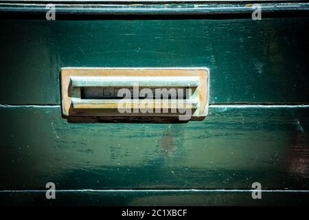 Buzón adornado en una puerta de madera verde antigua, forma tradicional de entregar cartas a una casa Foto de stock