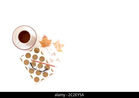 Escritorio blanco con taza de café, libreta, vasos, hojas de arce secas. Composición de otoño con espacio de copia. Foto de stock