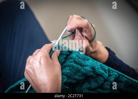 Las manos de una mujer tejiendo con lana. Foto de stock