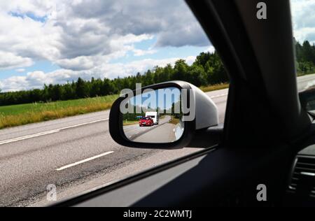 Motala, Suecia 20200618 mucho tráfico el día antes de la noche de verano. Coche y caravana en el espejo retrovisor, junto a la autopista 50 al norte de Motala. Foto Jeppe Gustafsson Foto de stock