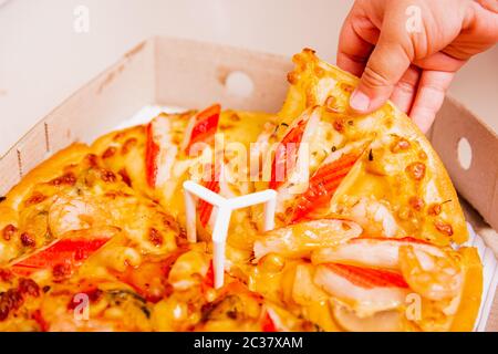 Comida casera caliente, comida italiana rápida vegetariana, entrega de la mano de niño pequeño Pizza pepperoni, queso muchas rebanadas en una caja de cartón abierta