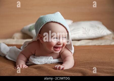 ute pequeño bebé yace en la cama envuelta en una toalla blanca con capucha