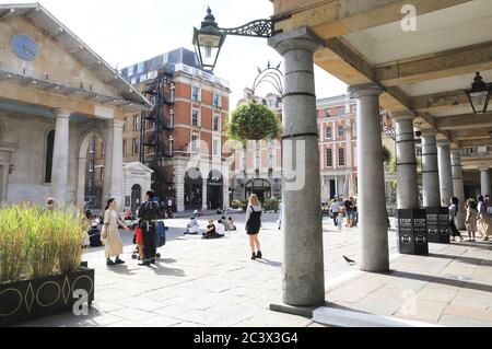 Disfrutando del sol en la Piazza en Covent jardín como la gente sale lentamente y alrededor de nuevo como las restricciones de coronavirus se levantan, en Londres, Reino Unido