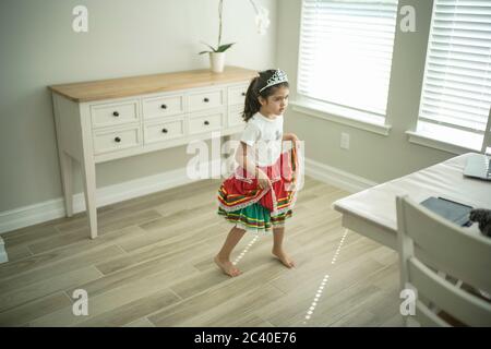 Chica disfruta de una clase de baile en línea con un ordenador portátil conectado a una televisión en casa