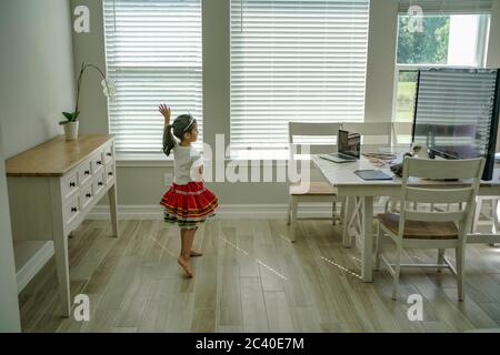 Chica disfruta de una clase de baile en línea con un ordenador portátil conectado a una televisión en casa