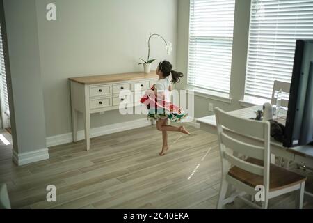 Chica disfruta de una clase de baile en línea con un ordenador portátil conectado a una televisión en casa