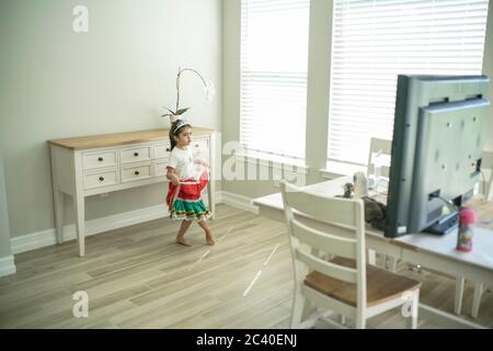 Chica disfruta de una clase de baile en línea con un ordenador portátil conectado a una televisión en casa