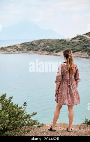 Grecia, vista trasera de una mujer mirando el Monte Athos en el mar