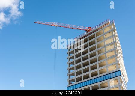 Obra con grúa en cielo azul - edificio moderno de oficinas y residenciales en construcción