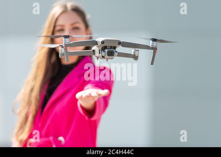 drone tierras en la mano, mujer joven desenfocada en el fondo, se centran en el quadcopter