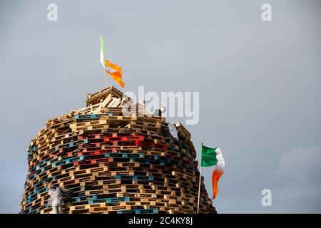 Fijar una bandera tricolor irlandesa en la parte superior de una hoguera en el área protestante Sandy Row de Belfast, Irlanda del Norte. Foto de stock
