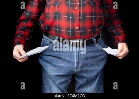 un hombre con jeans de color azul y una camisa roja a cuadros con bolsillos vacíos que sugieren un concepto de pobreza sobre un fondo negro Fotografía stock - Alamy