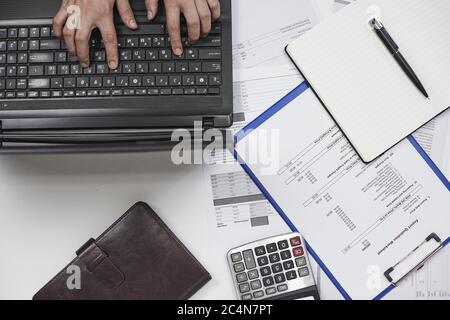 Vista superior de la persona que escribe en un teclado de la computadora haciendo papeleo financiero Foto de stock